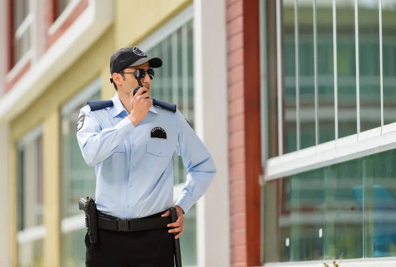 Security guard using radio outside building.