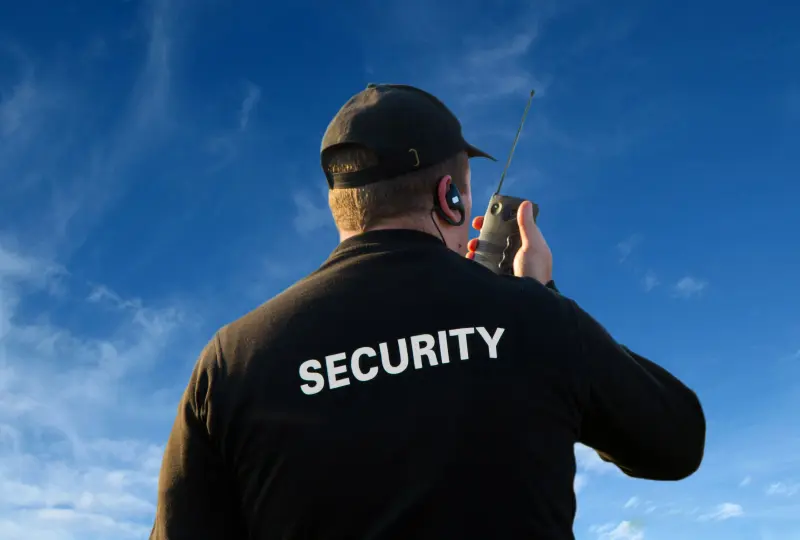 Security guard using radio under blue sky.